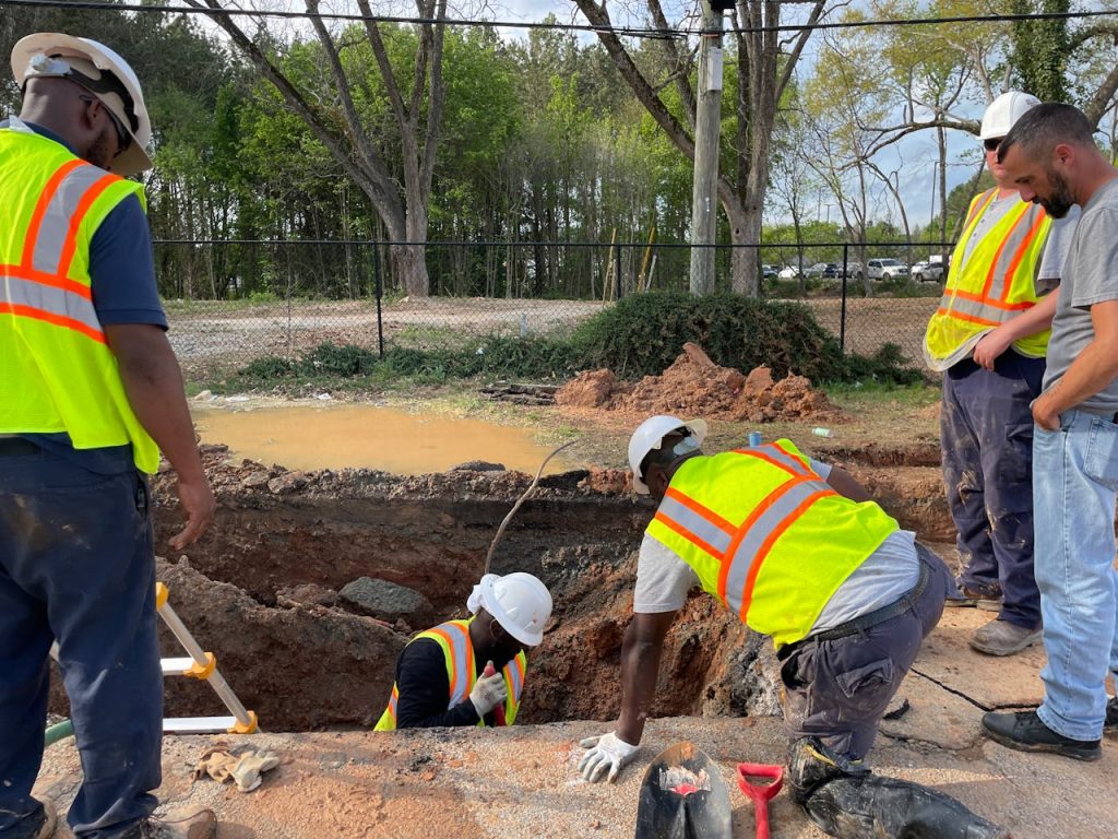 pexels photo 31460017 Team of construction workers inspecting an underground utility site on a sunny day.